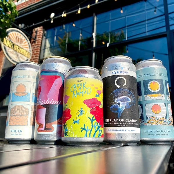 Five colorful beer cans with condensation sit on a table outside Underground Coffee and Ales.